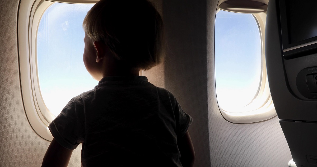 Child is watching from the window of the porthole for the flight of the aircraft