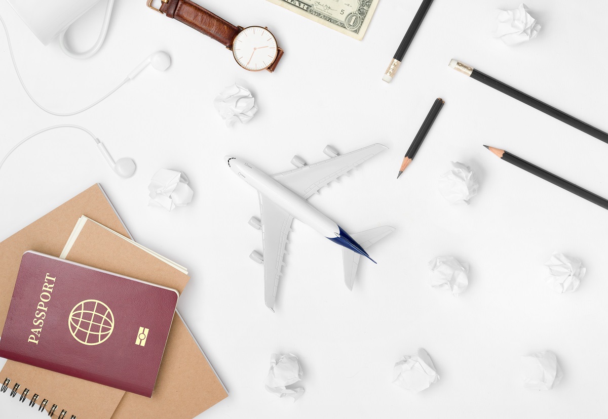 Travel Planning. Airplane, pencil, watch, money, paper note, notebook, earphone, and passport with blank space on white background. Preparation for Traveling and Flat lay Concept.